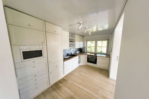 A kitchen with white cabinetry, a built-in oven, and a window providing natural light. - Holiday home with 2 bedrooms (Sasbachwalden)