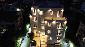 A multi-story building with illuminated windows and a central staircase. - Arbnor Hotel (Tirana)