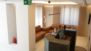 A hotel lobby with a reception desk, seating area, and a fire extinguisher. - Arbnor Hotel (Tirana)