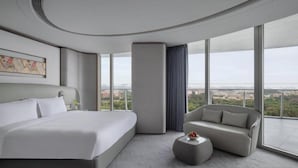 Habitació d'hotel moderna amb un llit gran, un sofà i vista a la ciutat.