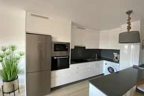 A modern kitchen with a refrigerator, oven, microwave, and washing machine. - Holiday apartment with 2 bedrooms (Morro jable)