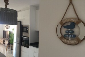 A modern kitchen with stainless steel appliances, a hanging light fixture, and a wall-mounted welcome sign. - Holiday apartment with 2 bedrooms (Morro jable)