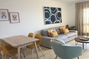 A living room with a sofa, a dining table with chairs, and a coffee table. - Holiday apartment with 2 bedrooms (Morro jable)