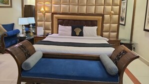Habitació d'hotel amb un llit gran, un sofà, una tauleta de nit i una làmpada.