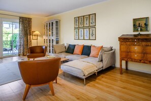 A living room with a sofa, armchair, and a cabinet. - Holiday apartment with 3 bedrooms (Garmisch-Partenkirchen)