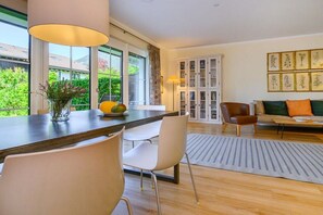 Ein modernes Wohnzimmer mit Essbereich, großen Fenstern und Blick ins Grüne.
