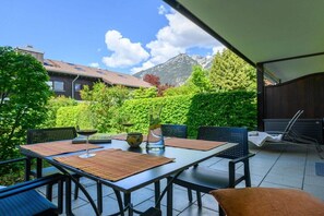 An outdoor patio with a table set for dining, surrounded by chairs, and a view of mountains in the background. - Holiday apartment with 3 bedrooms (Garmisch-Partenkirchen)
