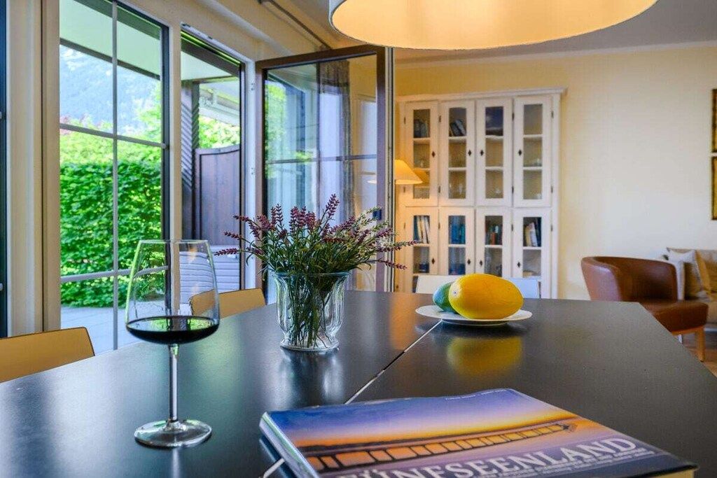 A dining table with a wine glass, a vase with flowers, and a book titled 'King Seidenland'.
