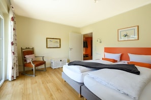 A hotel room with a bed, a chair, a door, and a window with curtains. - Holiday apartment with 3 bedrooms (Garmisch-Partenkirchen)