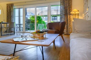 A hotel room with a bed, a dining table with glasses and a bowl, a chair, and a view of the outside through large windows. - Holiday apartment with 3 bedrooms (Garmisch-Partenkirchen)