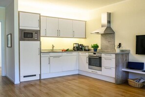 A compact kitchen with white cabinets, a microwave, an oven, and a coffee maker. - Holiday apartment with 3 bedrooms (Garmisch-Partenkirchen)