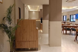 A hotel lobby with a reception desk, seating area, and a large plant. - Fortune Statue of Unity Ekta Nagar (Garudeshwar)