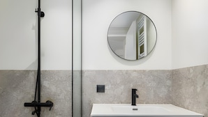A bathroom with a white sink, a black faucet, and a round mirror on the wall. - Celine: Apartments in the Center (Thessaloniki)
