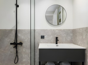 A bathroom with a white sink, a black faucet, and a round mirror on the wall. - Celine: Apartments in the Center (Thessaloniki)