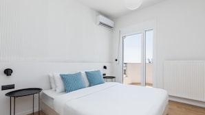 A modern bedroom with a large bed, a small bedside table, a wall-mounted air conditioner, and a sliding glass door leading to an outdoor area. - Celine: Apartments in the Center (Thessaloniki)