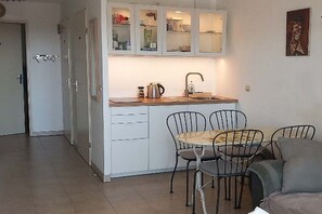 A compact kitchen with a dining area, featuring a sink, cabinets, and a table with chairs. - Holiday apartment with 1 bedroom (Antibes)