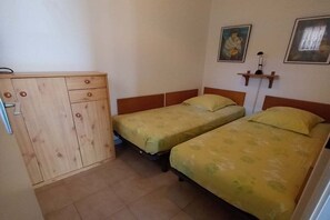 A room with two single beds, a wooden wardrobe, and a wall-mounted shelf with a lamp. - Holiday apartment with 1 bedroom (Antibes)