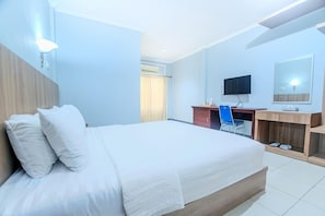 A hotel room with a large bed, a desk with a chair, a television, and a mirror. - Five Styles Kutai Permai (Sangatta)
