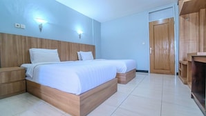 Een slaapkamer met twee bedden, een houten hoofdbord, nachtkastjes en een kledingkast.