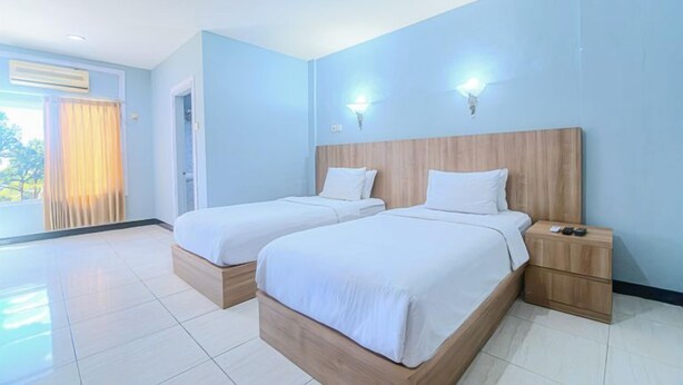 Een hotelkamer met twee bedden, een houten hoofdbord, een nachtkastje en uitzicht op de omgeving.