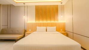 Een moderne slaapkamer met een groot bed, nachtkastjes en een zithoek.