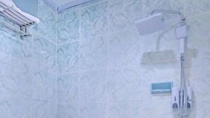 Een badkamer met toilet, douche en betegelde wand.