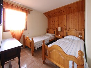 A bedroom with two wooden beds, a wooden desk, and a window with curtains. - Casa Sibylle EG (Candelaria)