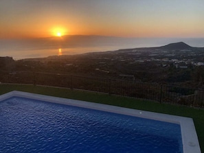 A swimming pool with a view of the sunset over the sea and a distant mountain. - Casa Sibylle EG (Candelaria)