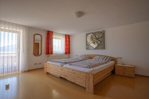 A bedroom with a wooden bed, a nightstand, a mirror, and a window with curtains. - in the Weber holiday home (Hopfen am See)