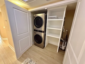 A compact laundry room with two stacked washing machines and a shelf labeled 'Sleepers Safe.' - South Tower-10th Floor-2BR/2BA Custom Design & Professionally Decorated-All New! (Myrtle Beach)