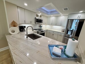 A modern kitchen with a central island, stainless steel appliances, and a skylight. - South Tower-10th Floor-2BR/2BA Custom Design & Professionally Decorated-All New! (Myrtle Beach)