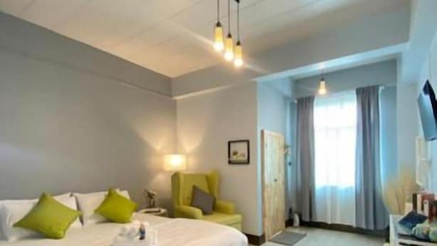A hotel room with a bed, bedside table, lamp, and a view of the hallway. - Triple J Hotel Trang (Trang)