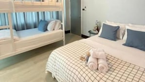 A hotel room with a bunk bed, a single bed with a checkered bedspread, and a bedside table with a lamp. - Triple J Hotel Trang (Trang)