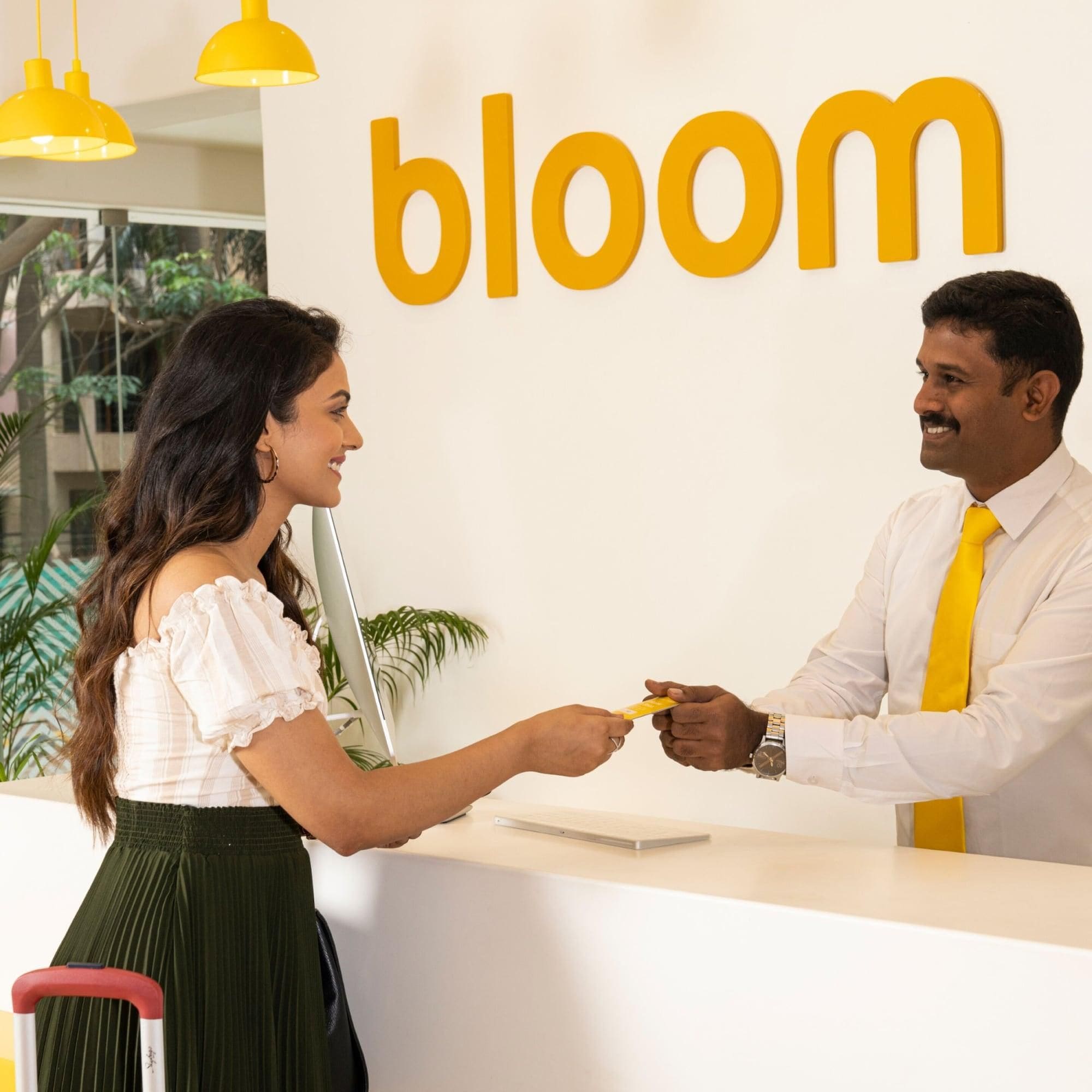 A reception desk with a 'bloom' sign, a laptop, and a plant in the background.