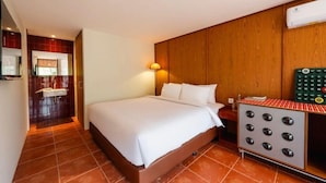 A hotel room with a bed, a nightstand, a wall-mounted heater, and a bathroom with a sink and mirror. - Aksara Hotel by Aruna Group (Bandung)