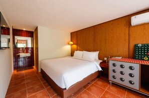 Habitació d'hotel amb llit, una taula de nit, un escalfador fixat a la paret i un bany amb rentapins i mirall.