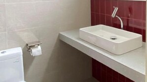 A bathroom with a white sink, a mirror, and a toilet. - Aksara Hotel by Aruna Group (Bandung)
