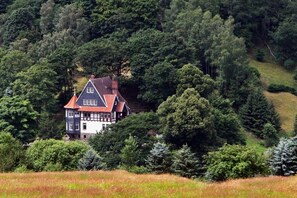 Ein traditionelles Haus, umgeben von dichtem Wald.