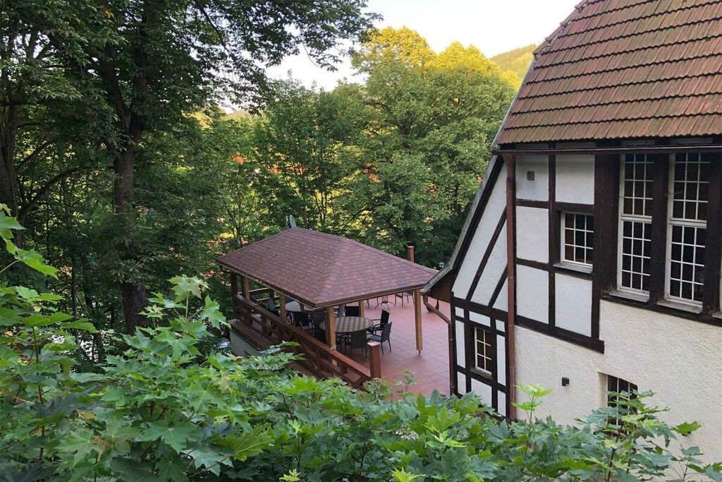 Ein traditionelles Fachwerkhäuschen mit einer überdachten Außenveranda und einer Treppe, die zu einem zweiten Stock führt.