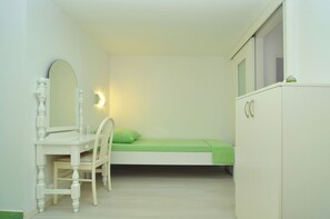 A small, white bedroom with a single bed, a desk with a chair, a mirror, and a wardrobe. - Spacious modern apartment with big patio and sea view (Slatine)