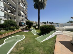 A residential area with a pool, a palm tree, and a building with balconies. - Apartment 'In Parador Area Nerja' with Sea View, Shared Pool and Air Conditioning (Nerja)