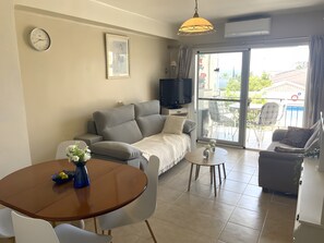 A living room with a sofa, a TV, a dining table with chairs, and a balcony with outdoor furniture. - Apartment 'In Parador Area Nerja' with Sea View, Shared Pool and Air Conditioning (Nerja)