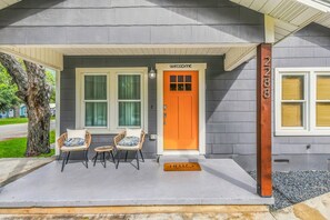 A house with a porch, a bright orange door, and a welcome mat. - Gruene Road Cottage - New Braunfels (New Braunfels)