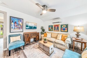 Ein Wohnzimmer mit einer Couch, Sesseln, einem Couchtisch und Kunstwerken an den Wänden.
