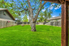 Ein Garten mit Holzzaun, einem Baum und einem Haus im Hintergrund.