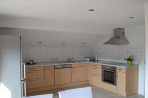 Une cuisine moderne avec des meubles en bois, un four encastré et une hotte en acier inoxydable.