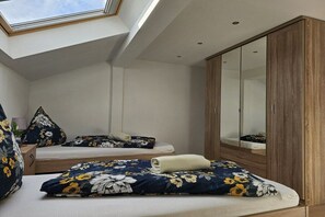 Une chambre avec un puits de lumière, un lit avec une literie à motifs floraux, une armoire et un miroir.