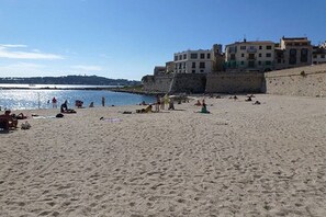 A sandy beach with people, a body of water, and buildings in the background. - Holiday apartment with 1 bedroom (Antibes)