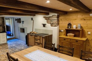 Un intérieur en bois comprenant une table à manger, des chaises, un coin cuisine et un mur en pierre.