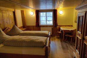 Une chambre confortable avec deux lits, une petite table et une fenêtre.